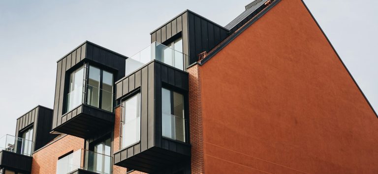 PortalDiez.com - Vivienda / Archivo Edificio moderno con paredes rojas y balcones oscuros en la parte superior.