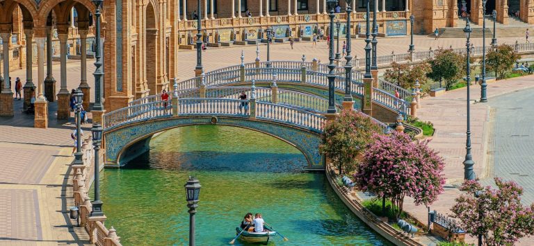 portaldiez.com - Sevilla /Archivo Puente sobre el canal frente a un majestuoso edificio de estilo regionalista en Sevilla.